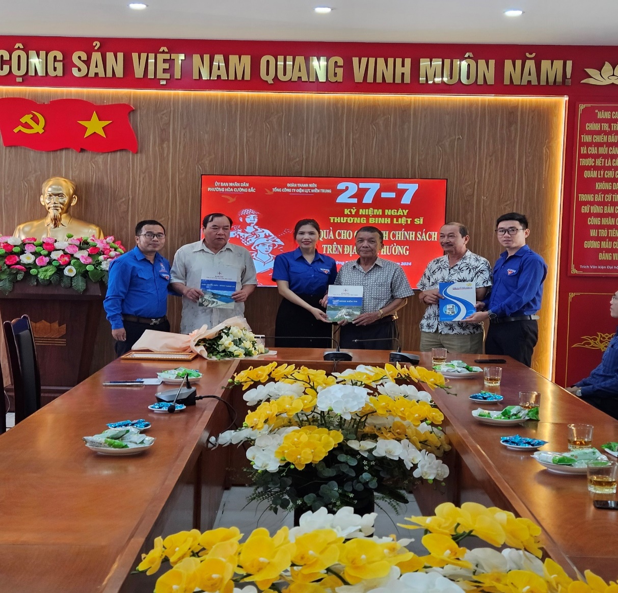 A group of people standing around a table with flowers

Description automatically generated